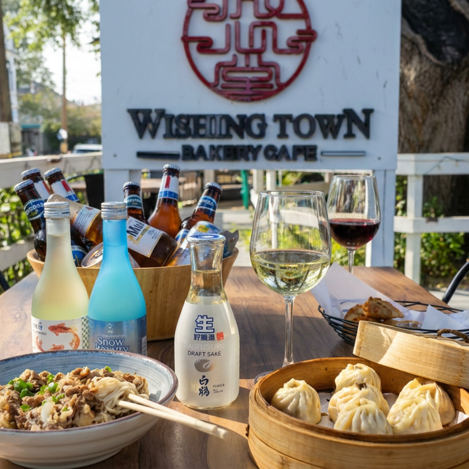 Outdoor table at WiseMing Town Bakery Cafe with dumplings, noodles, wine, sake, and bottled drinks.